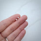sterling silver kitten tooth stud earrings in a hand for scale jaci riley jewelry